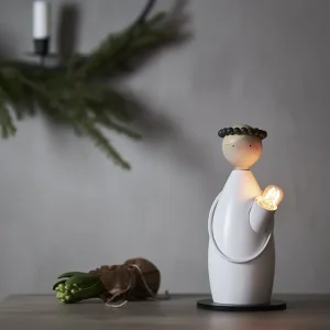 Holzleuchter Lucia Classic blond mit leuchtendem E14-Lämpchen auf Tisch, nordisches Ambiente mit Tannenzweig im Hintergrund