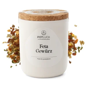 Weiße Potluck-Dose mit der Aufschrift ‚Feta Gewürz‘, flankiert von bunter Gewürzmischung aus getrockneten Kräutern und Gemüse