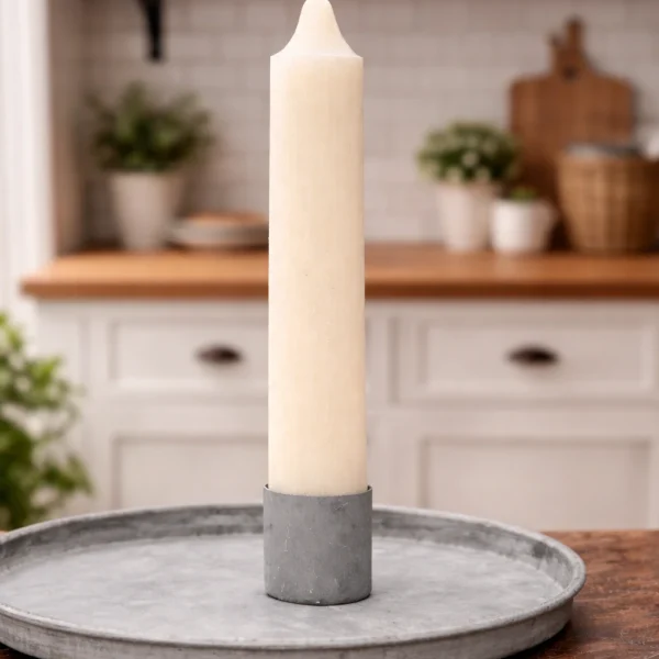 Cremefarbene Stabkerze in grauem Kerzenhalter auf rundem Metalltablett