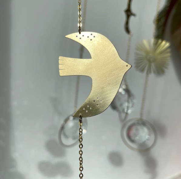 Goldfarbener Sonnenfänger Birdie mit Vogelmotiv, Messingkette und Kristallglas-Prisma am Fenster