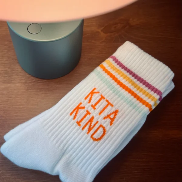 Weiße Kita Kind Socken von Loones mit Pastellstreifen und orangefarbenem Schriftzug