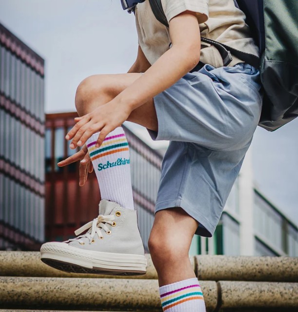 weiße Schulkind Socken von Loones mit bunten Streifen und petrolgrünem Schriftzug