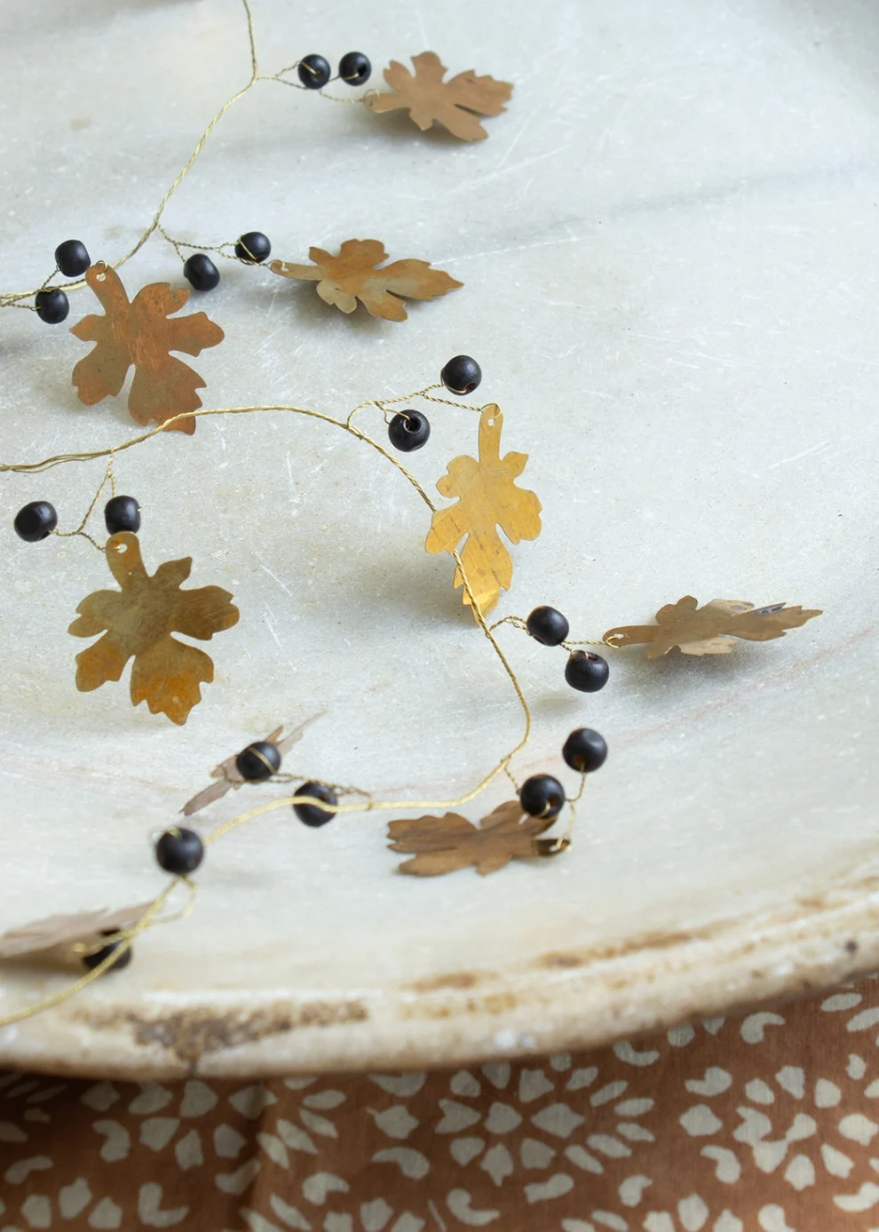 Handgefertigte Girlande mit goldfarbenen Eichenblättern und schwarzen Holzperlen